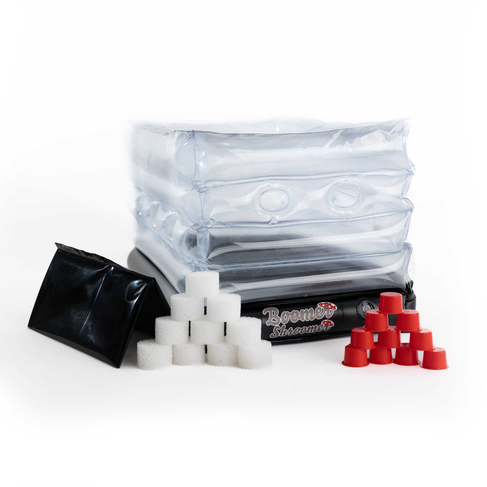 An inflatable monotub kit by Boomer Shroomer, including a clear plastic monotub, white and red caps for mushroom cultivation, and a black removable liner.