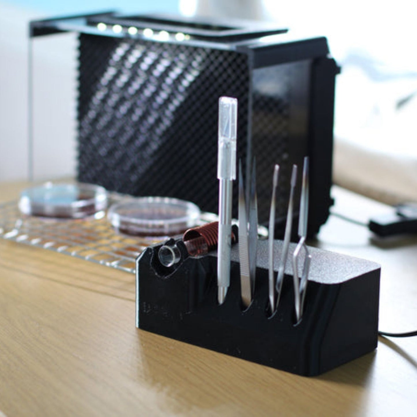 black induction steriliser for mycology work by funguy equipment with scalpel tools in holder infront of a laminar flowhood